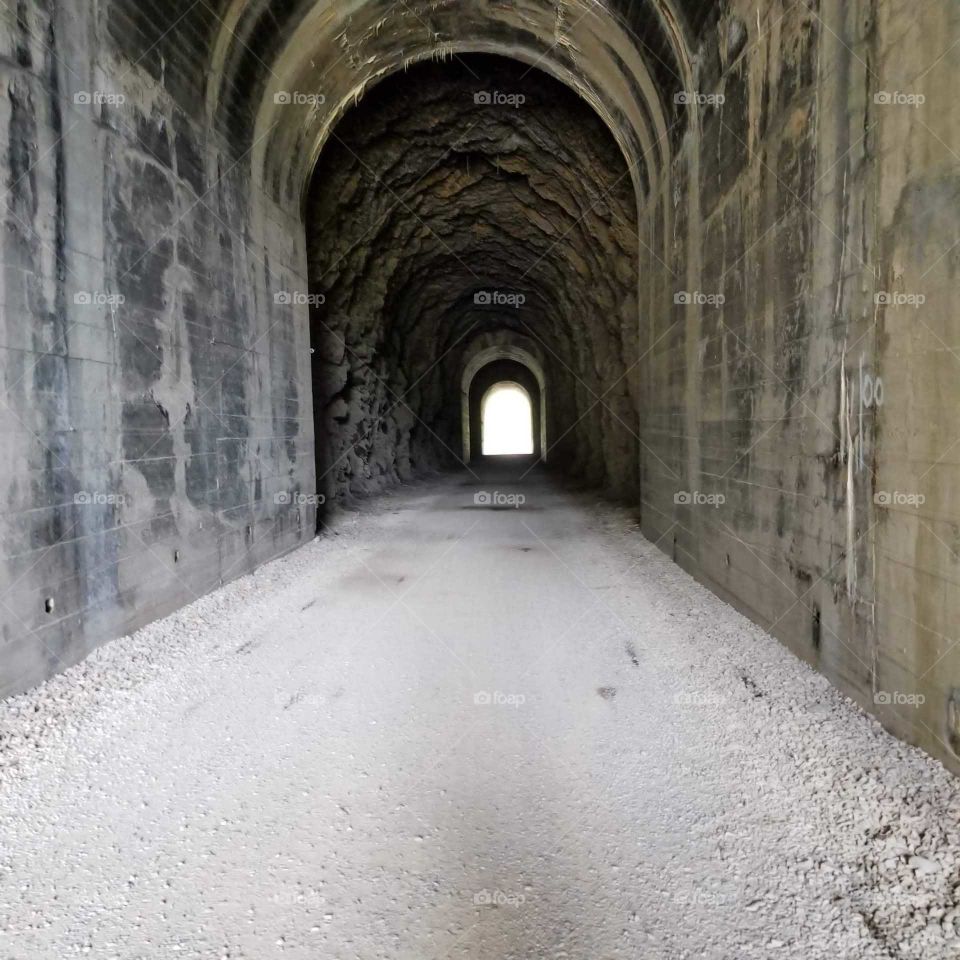 old railroad tunnel on a mountain hike with light shining thru the opening