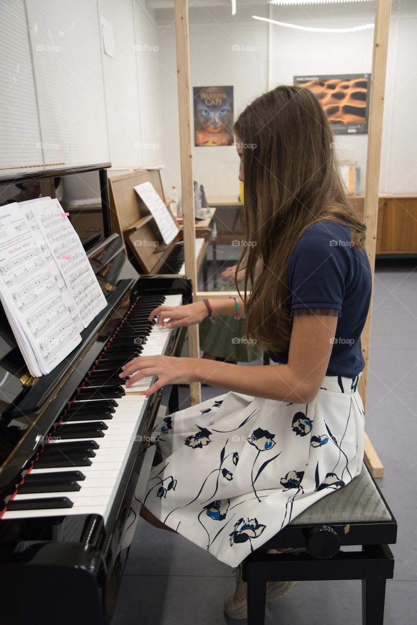 teenage girl playing the piano in the concert hall, hobby, playing music on the instrument

