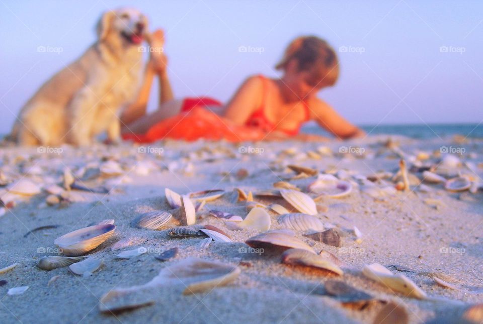 girl lies on the beach with a dog