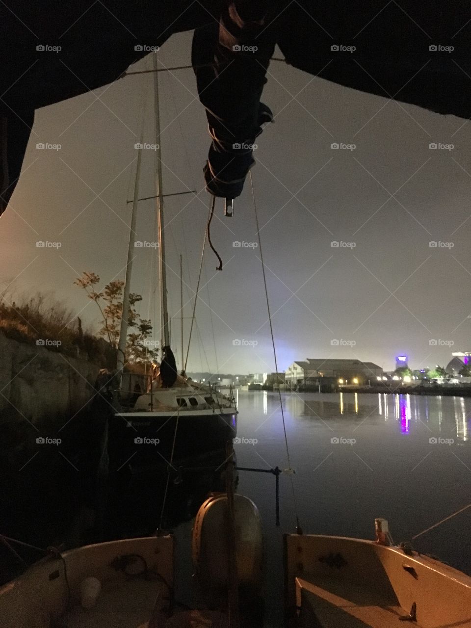 A nighttime view from the “Salvation” looking out the front deck onto the East River at Newtown Creek, LIC Queens, NY. The neon lit buildings in the distance cast beautiful colored reflections onto the sea. Photo from 2018. Hypnotic Productions