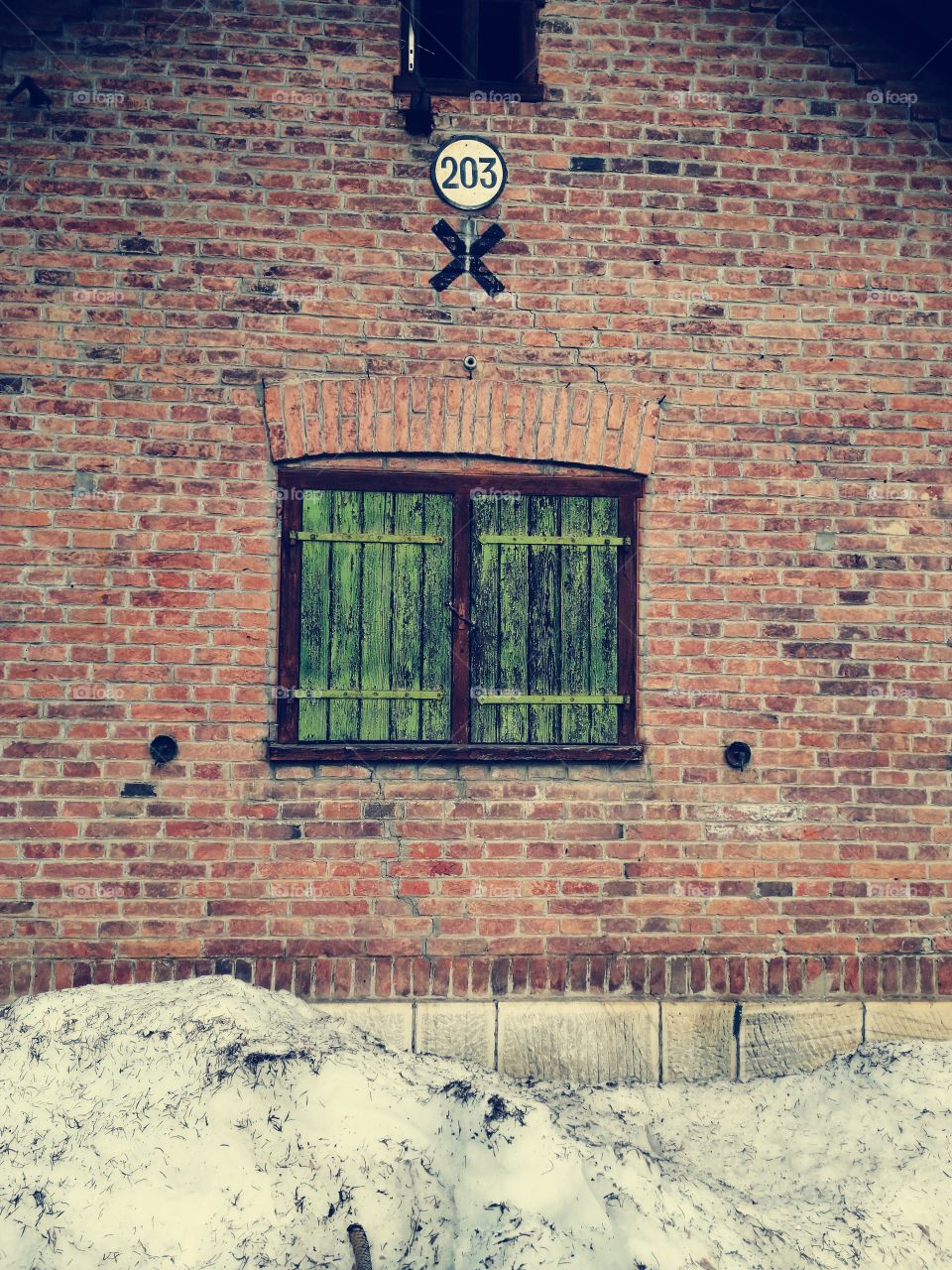 Window with closed wooden made shutters at brick wall
