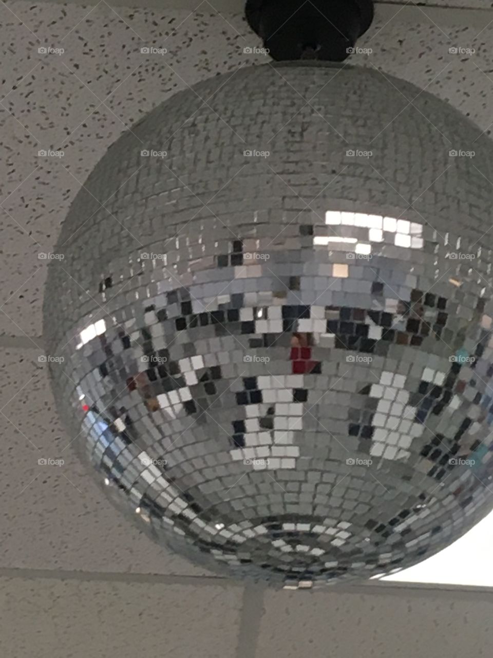 Silver disco ball all shiny hanging from the ceiling. Reflecting all that it sees!
