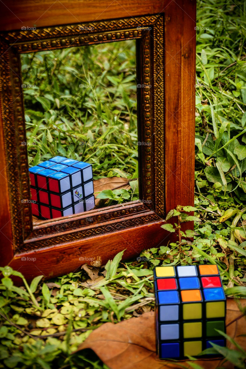 Composition of an unarmed rubik's cube and in the mirror it reflects an armed cube.  Double exposure
