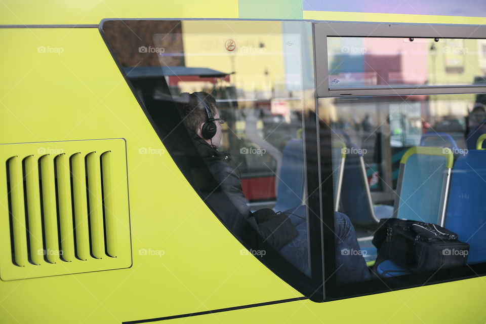 boy on a bus listening music on headphones. guy with headphones on a yellow bus