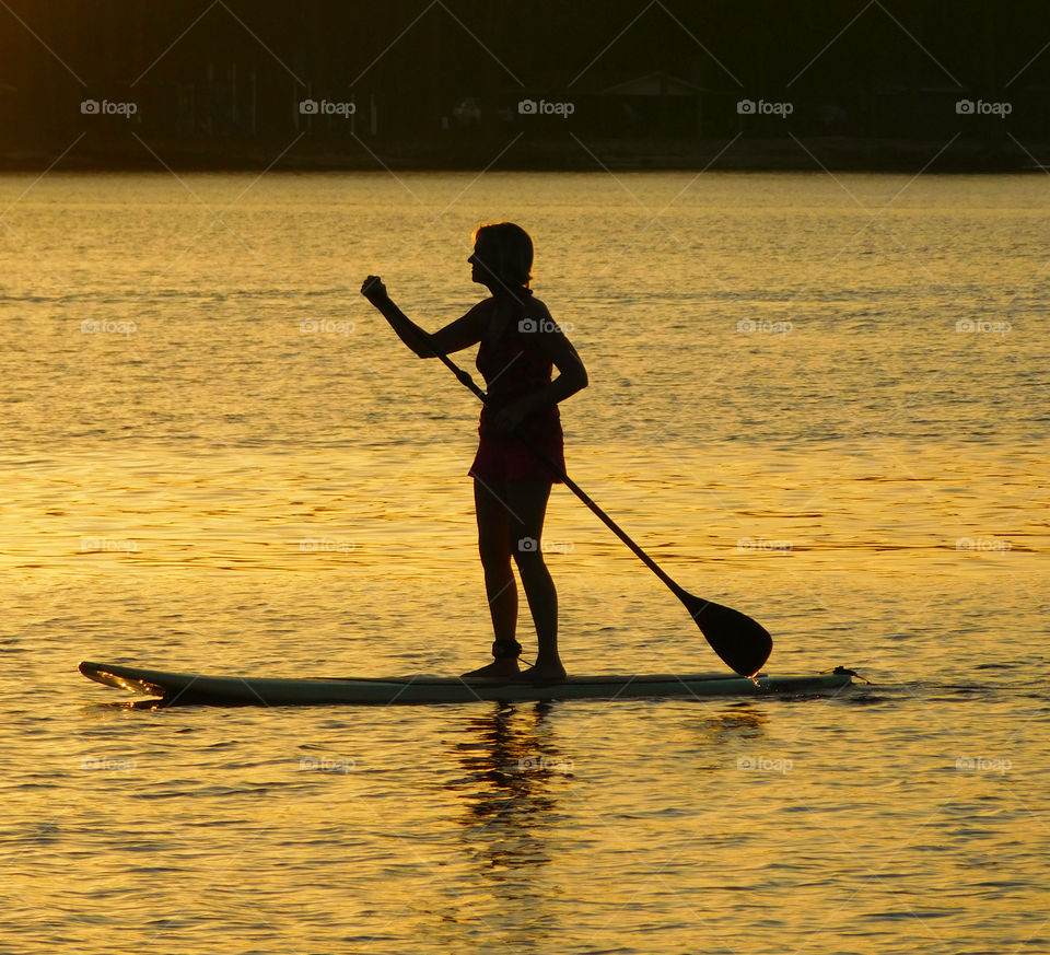 Silhouette of girl standing on paddle board