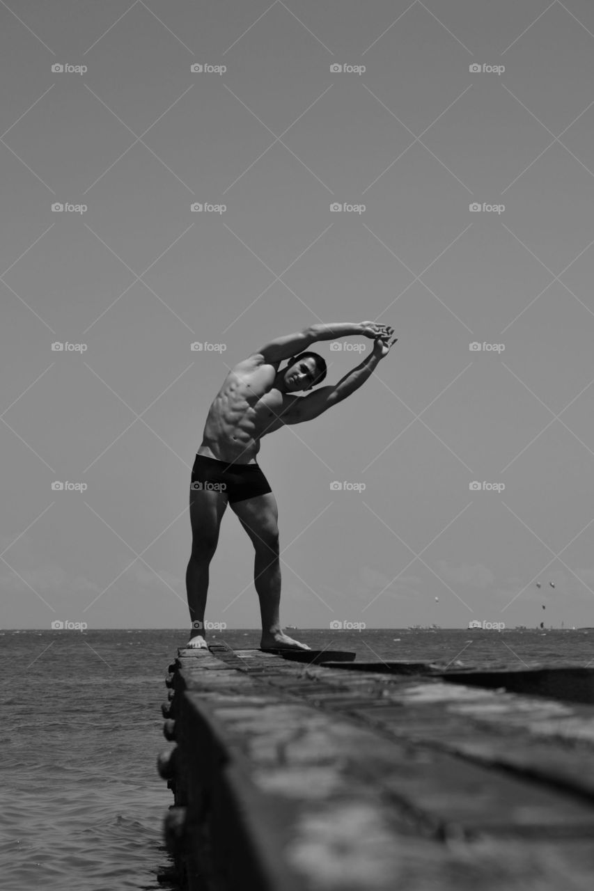 Muscular man stretching on pier