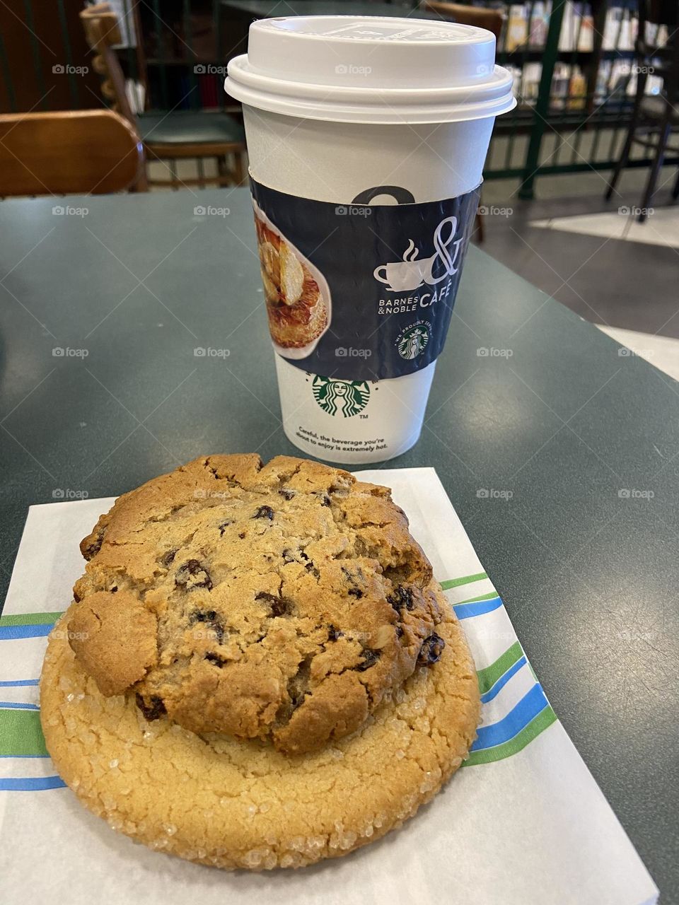 Two cookies, one oatmeal raisin and the other sugar, on top of a bakery bag, near a cup of tea. All were from the Barnes & Noble Cafe, a good place for a mid-day break, especially if you like a side of reading with your treats.