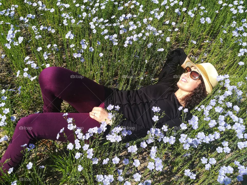 Girl relaxes in a field of flax flowers