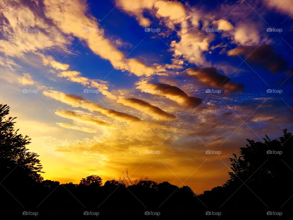 Brilliant blue and orange sunset with whimsical floating clouds 