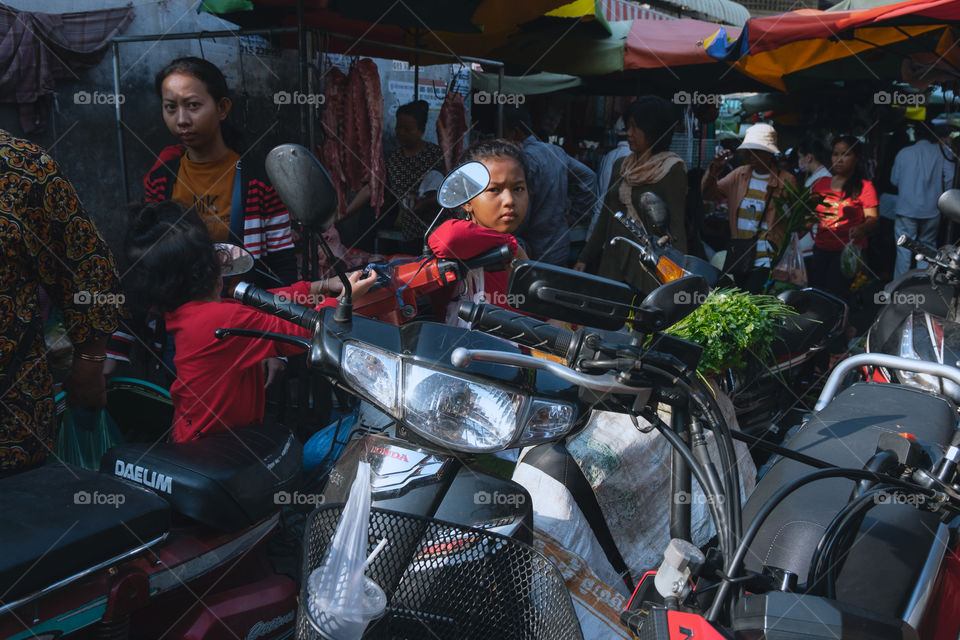 Children sitting on motorcycle waiting in the market 