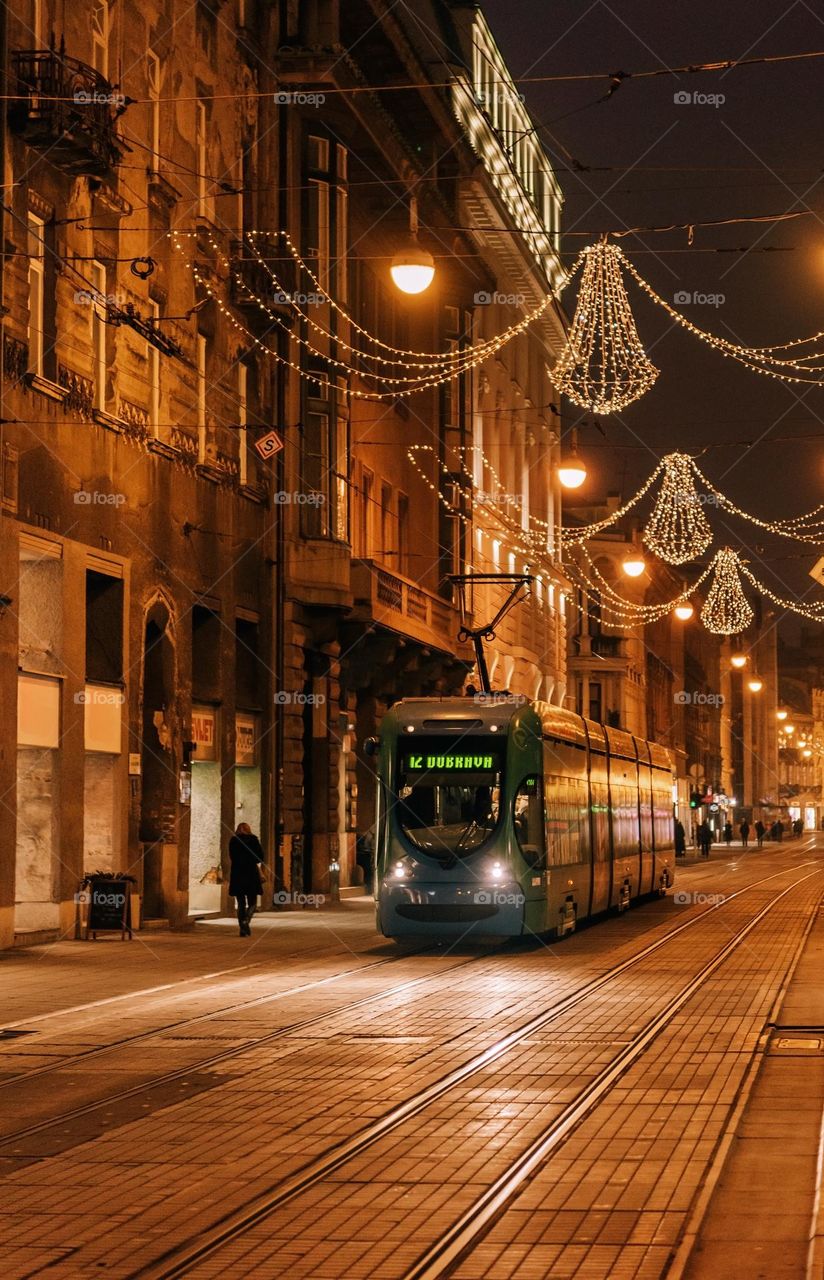 Night photo of tram on street in city of Zagreb decorated with christmas lights in december.
