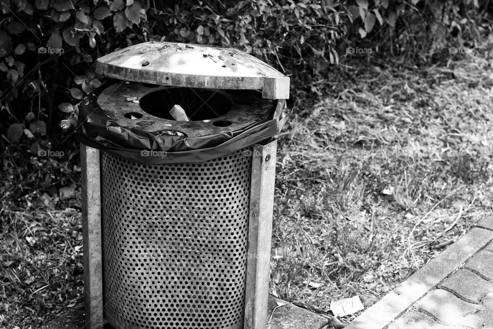 Black and white photo of a trash can in the city