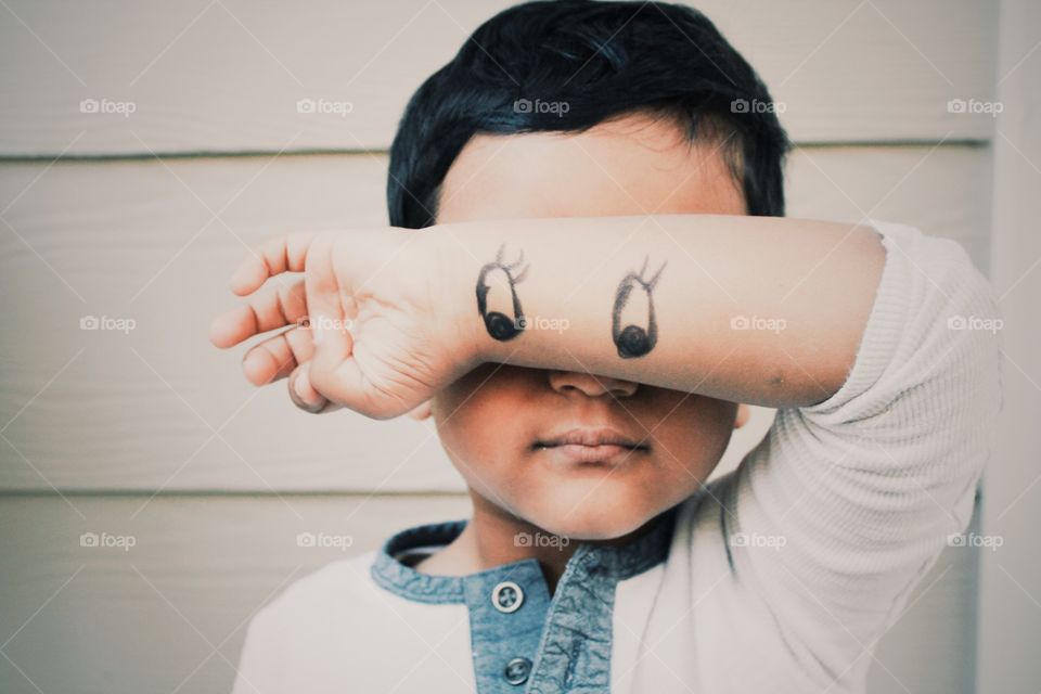 Close-up of a child with eyes drawn on his wrist