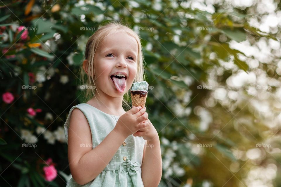 Candid portrait of happy little Caucasian girl eating icecream outdoor