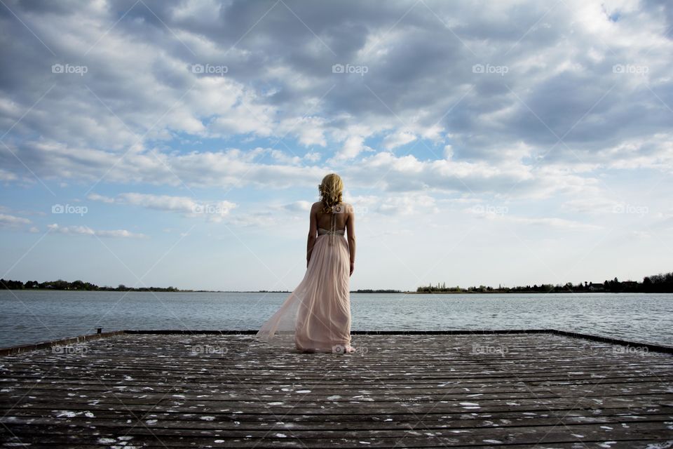 woman in amazing surrounding. woman standing on a wooden deck at lake with amazing view