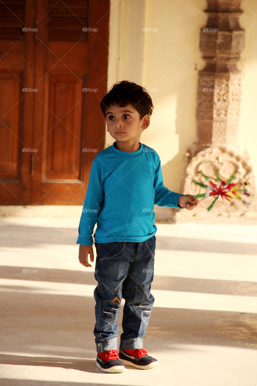 Indian boy with a fan toy in a royal palace