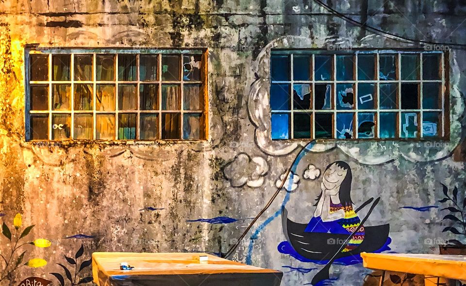 A mural of a girl in a row boat by an unknown artist adorns a wall of broken windows in Minde, Portugal 