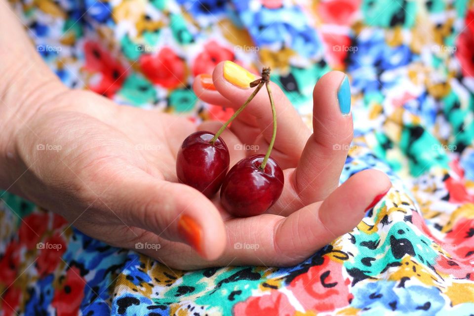 Hand holds cherry, colorful background