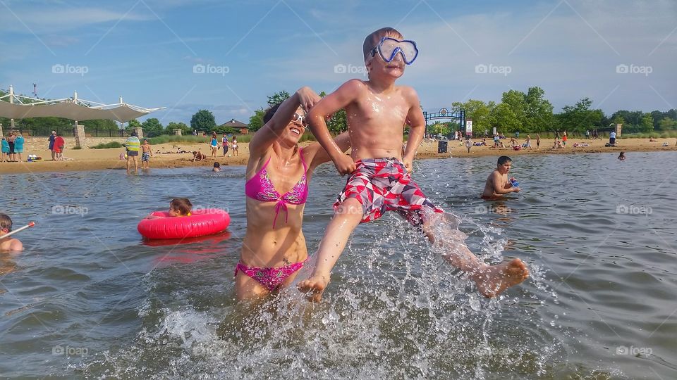 "throw me mommy" playing at the beach. splashing and getting thrown into the water.