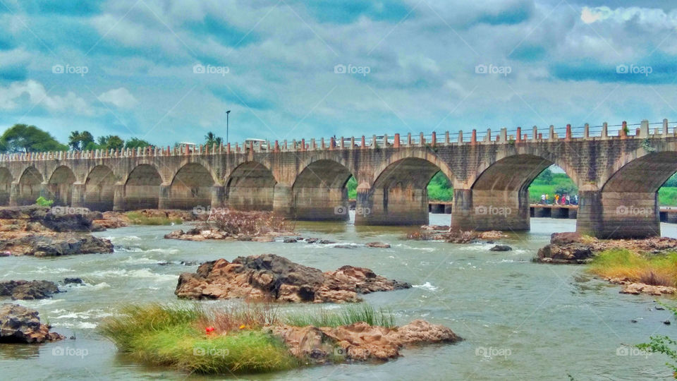 Landscape portrait, This photograph shows construction, design, shape of old bridge having beautiful scenery or surrounding river ,sky.