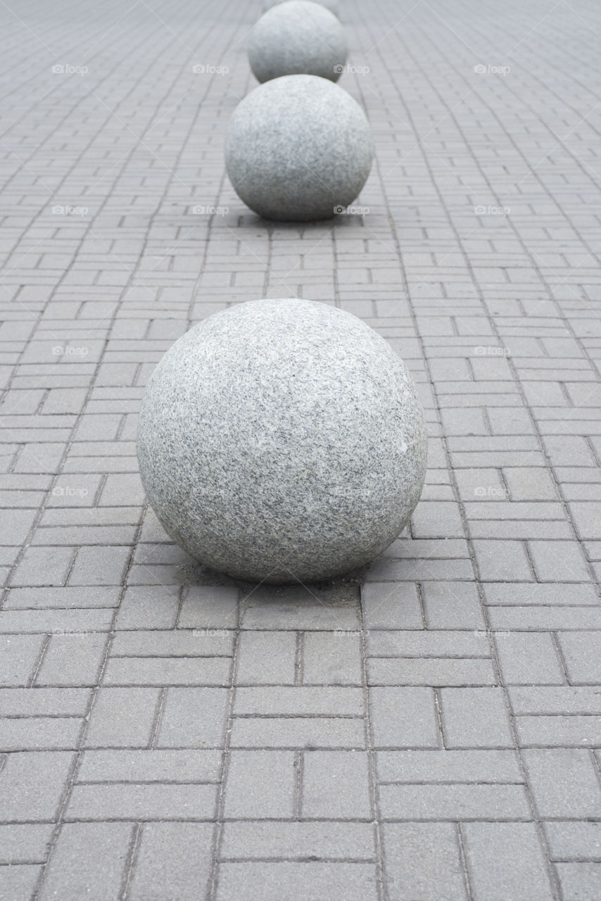 A large stone balls lies on a stone pavement