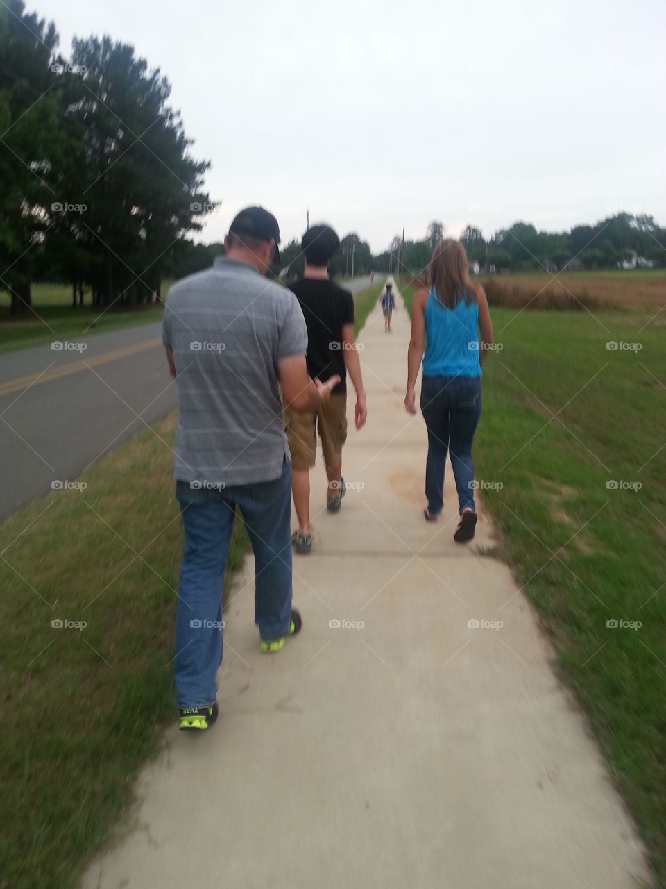 Mother and father walking on the sidewalk with their boys in the summer. 