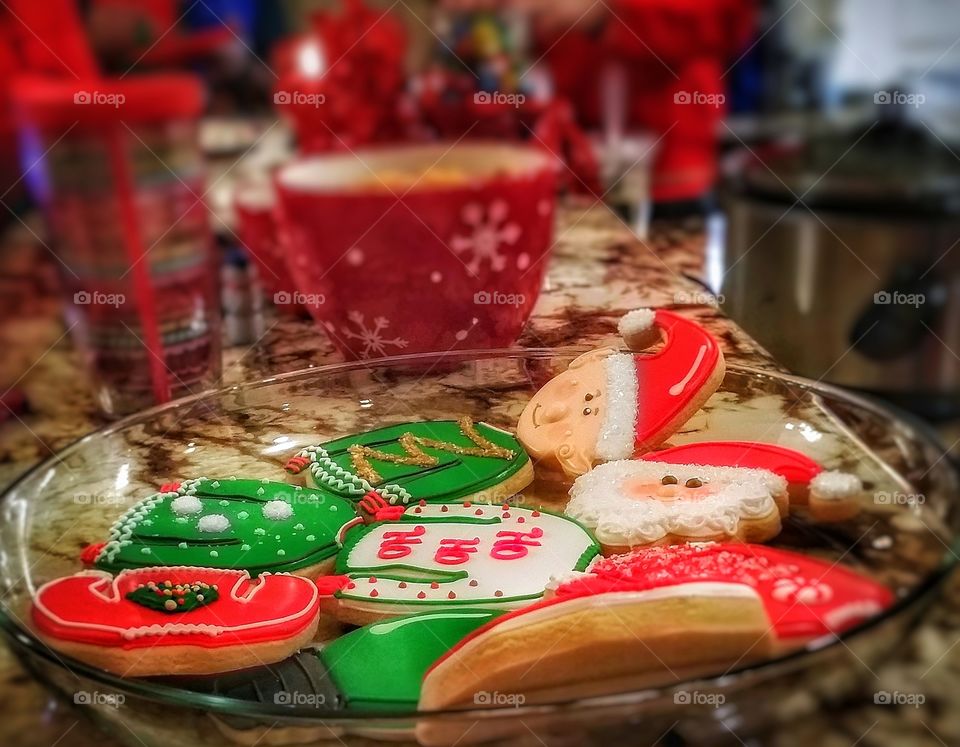 Iced Christmas cookies Santa Claus elves sweaters on a granite counter with other treats at an ugly sweater holiday party