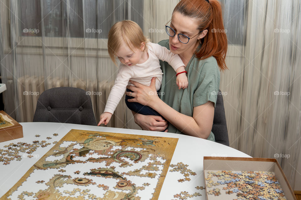 Woman is solving puzzle in quarantine with baby girl