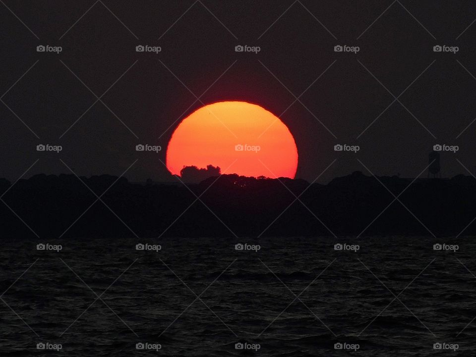 The big orange and crimson ball slowly going down and down and it sets into the horizon making the sky absolutely stunning