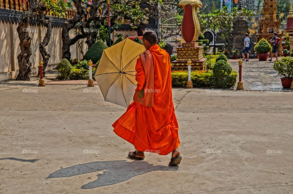 Escaping the heat. Monk in Cambodia unfold his umbrella to cover from heat