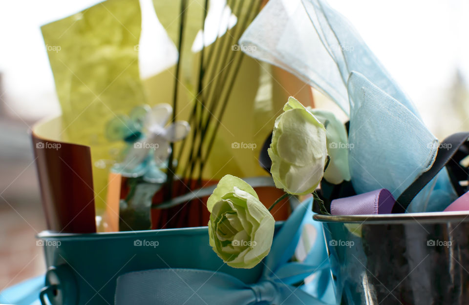 Decorative paper art supplies in buckets with bows and cut outs for making paper flowers and decorating cards on windowsill 