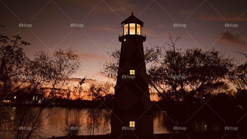 Backlit Sunset reflections of mirrored Lake Waters galore Lighthouse standing Firm. Twilight Sunset Completing to Night. 