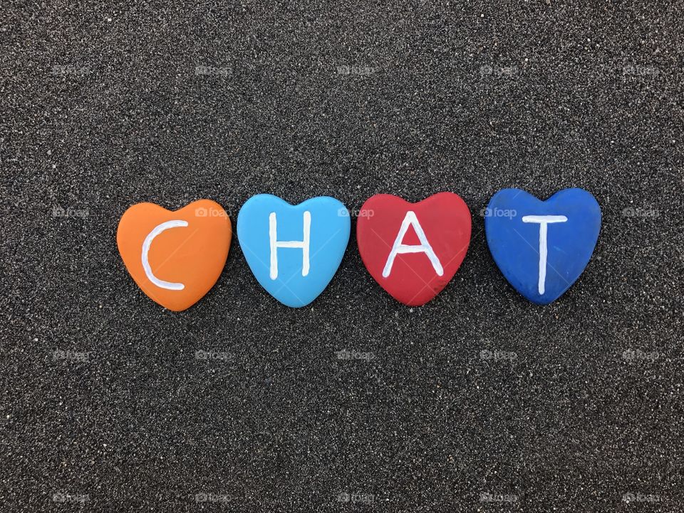 Chat word with colored heart stones over black volcanic sand