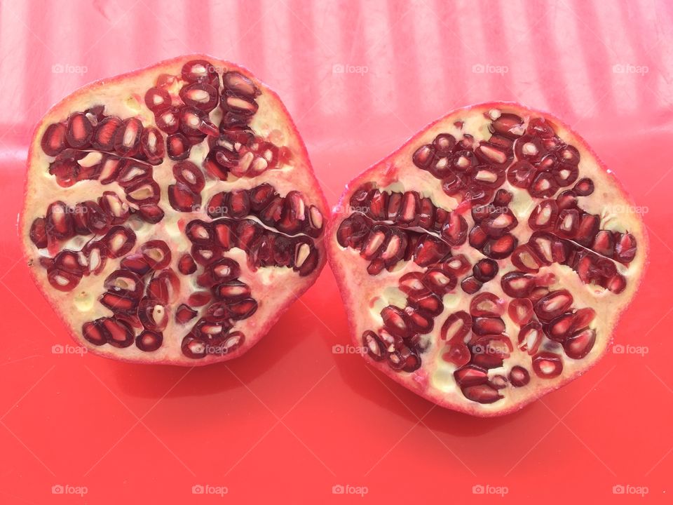 Two half pomegranate on red table outside 