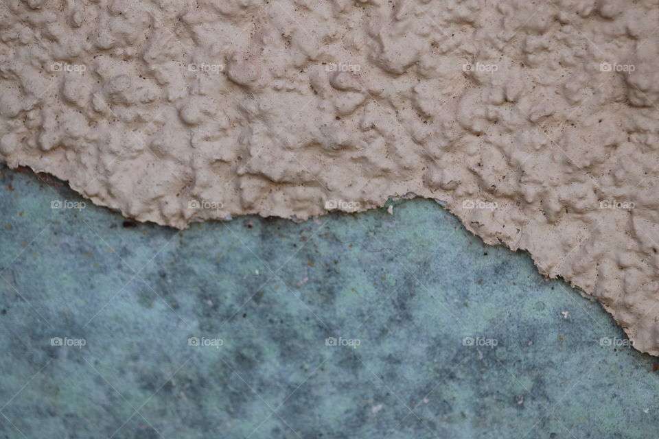 Double textures. Stucco lifting from old painted exterior wall showing original paint 