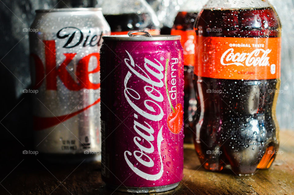 A Diet Coke and a cherry Coca-Cola and a bottle of Coca-Cola with condensation drops