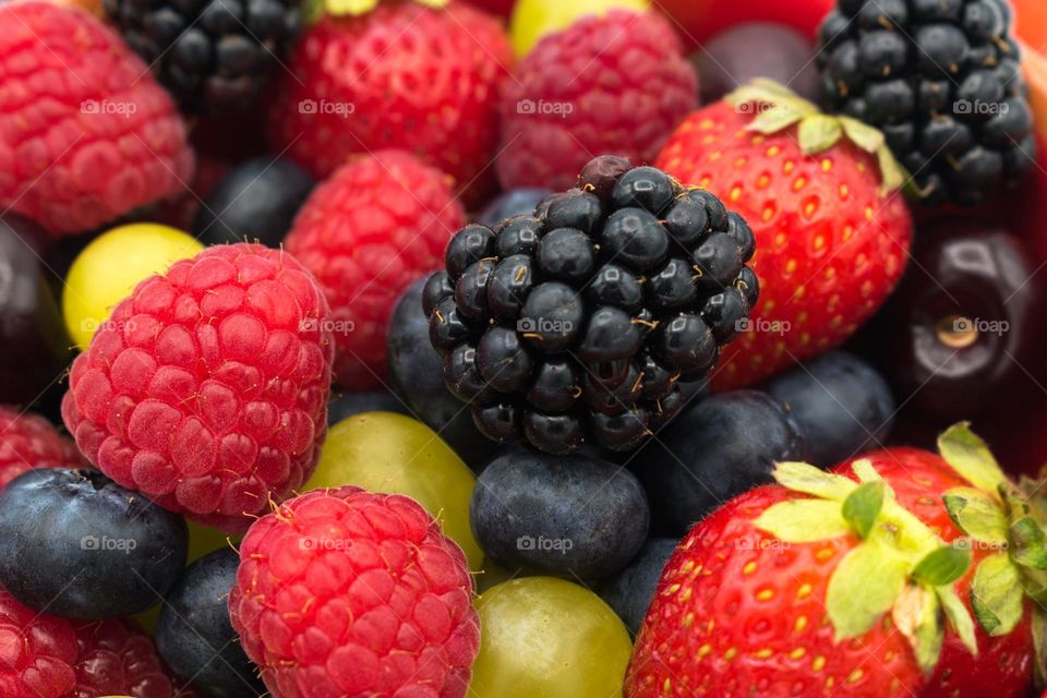 Close-up image of mixed fruits: forest fruits (blackberries, raspberries, blueberries  and strawberries), cherries and grapes.