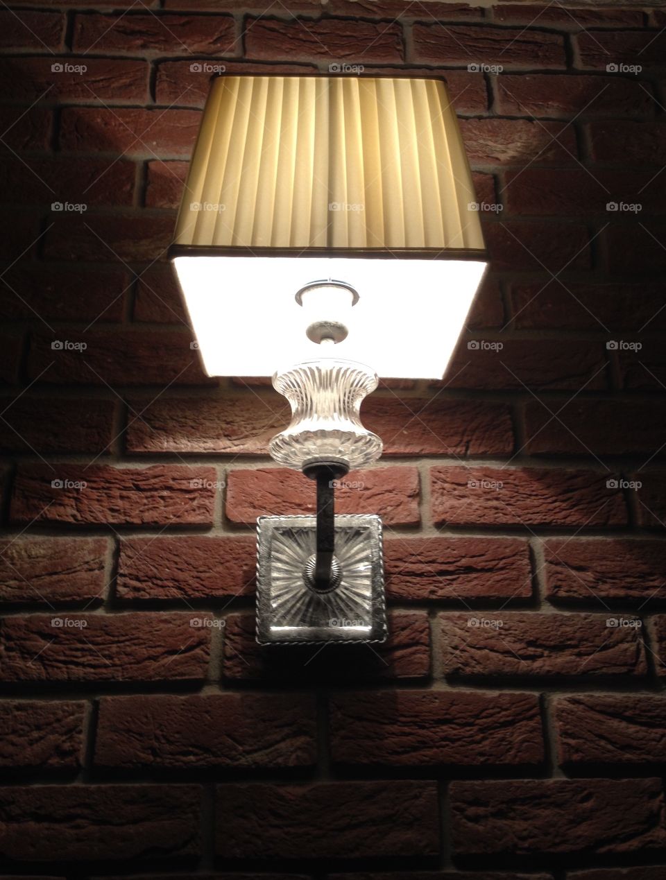 A square lamp on a wall of bricks 