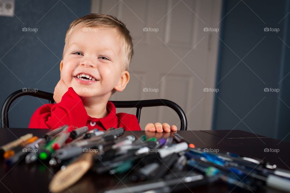 Happy boy with pens at a desk