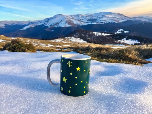 Snowflakes Christmas mug placed on snow with snowy mountains in the background