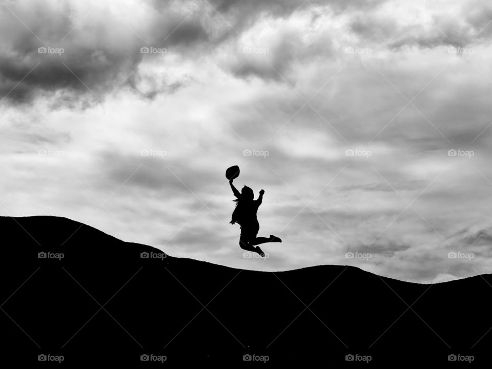 Jubilant lady jumping on top of a mountain slope