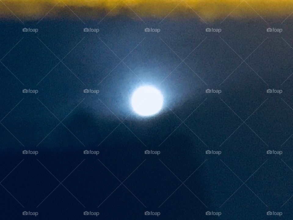 Another unusual photograph from 2018 of the full moon in the night sky over Long Island City, Queens, NY. The moon appears as if resting in a “cradle” made up of mist and clouds. Hypnotic Productions