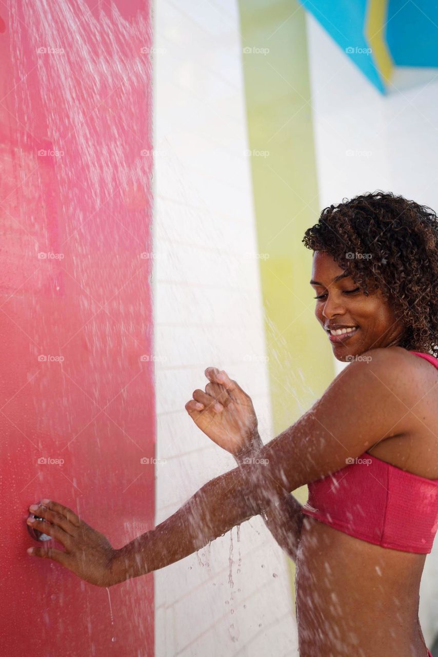 Black woman with Afro hair using outdoor shower
