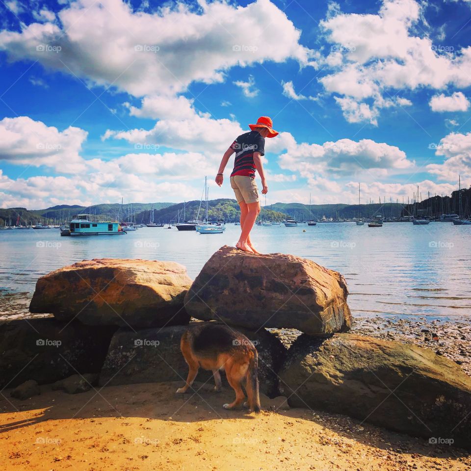 Boy on a rock with a dog at the beach 