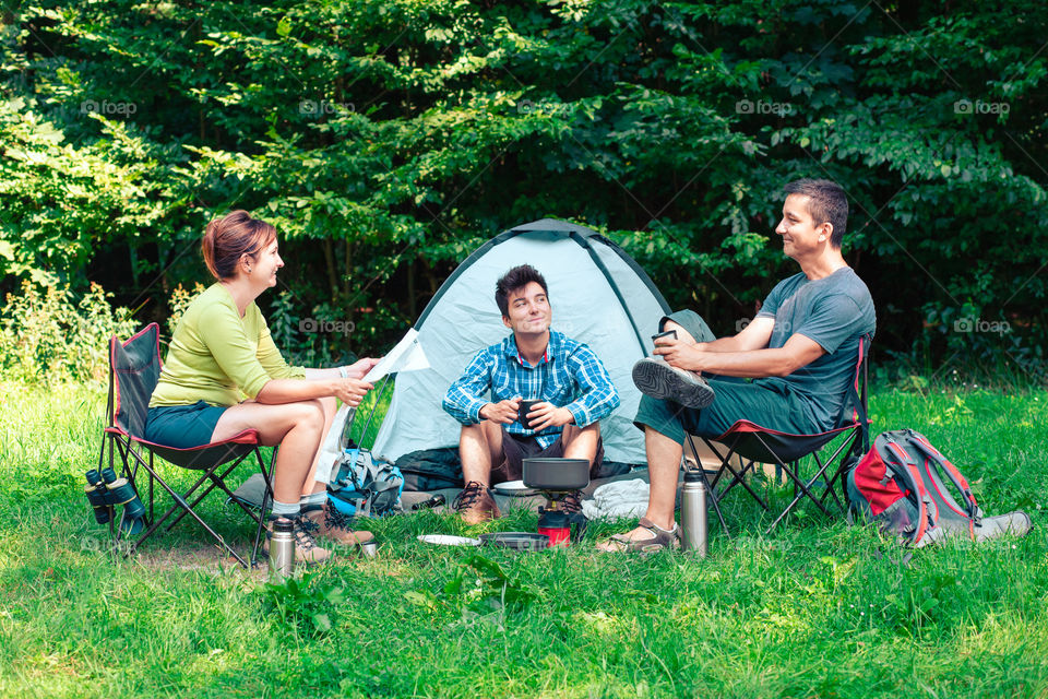 Spending a vacation on camping. Preparing a meal outdoor next to tent. Planning next trip