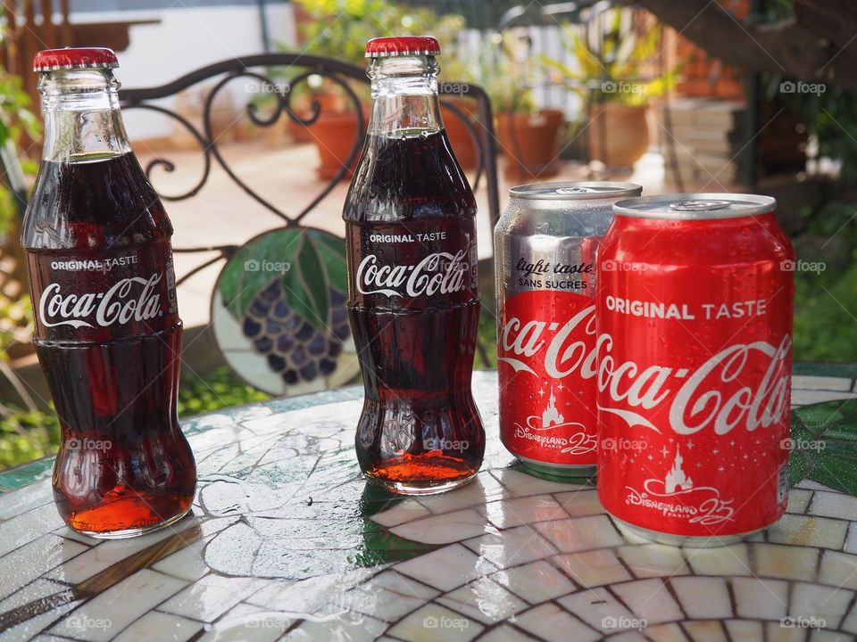 Coca Cola bottles and cans on garden table.