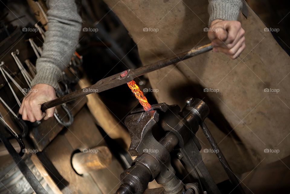 Blacksmith working at with metal at forge