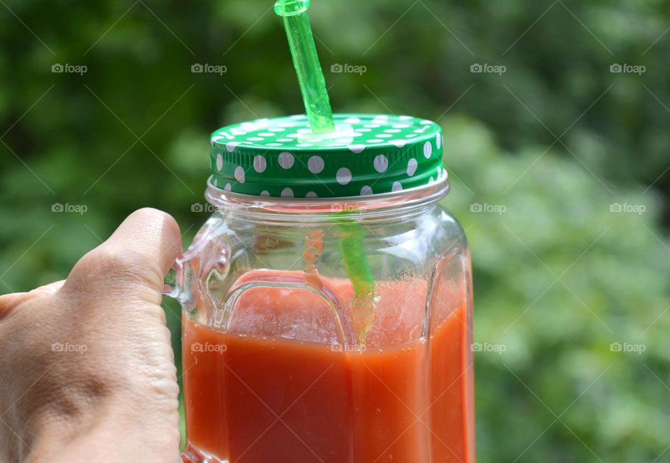 tomatoe juice in cup in the hand green background tasty healthy food