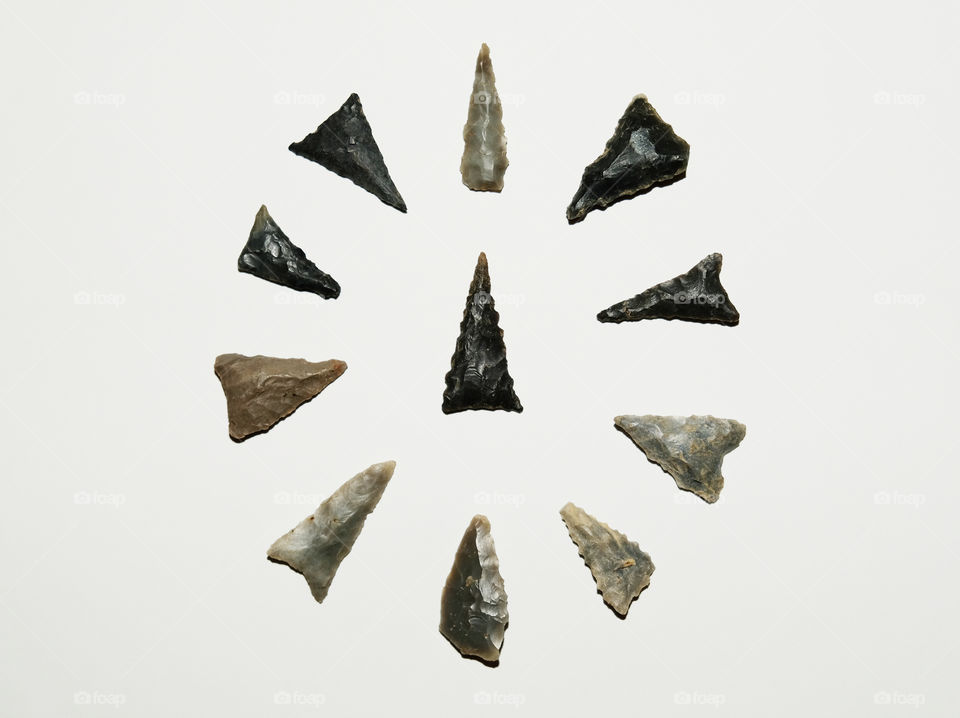 Several arrowheads or bird points arranged in a circular array with a centerpiece on white background. All found in Tennessee.