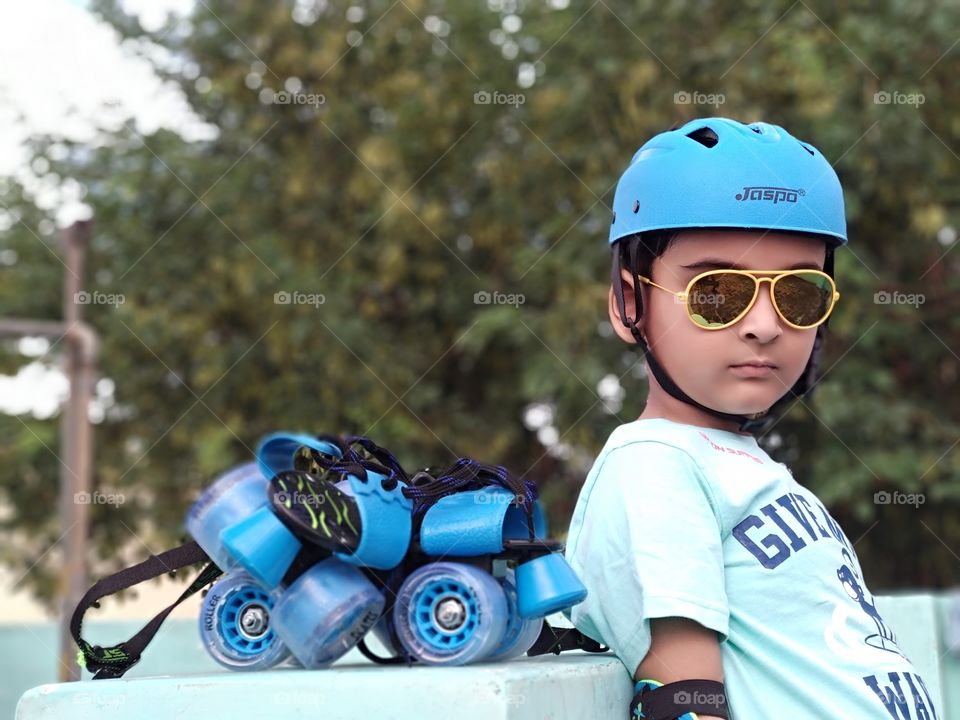 Indian boy with skates, sunglasses and helmet. Sports portrait.